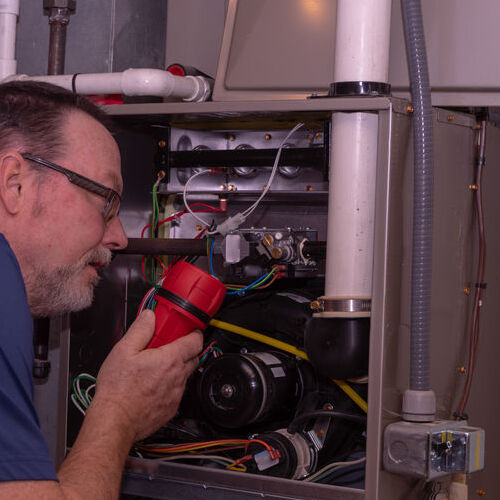 An HVAC Technician Examines a Gas Furnace.