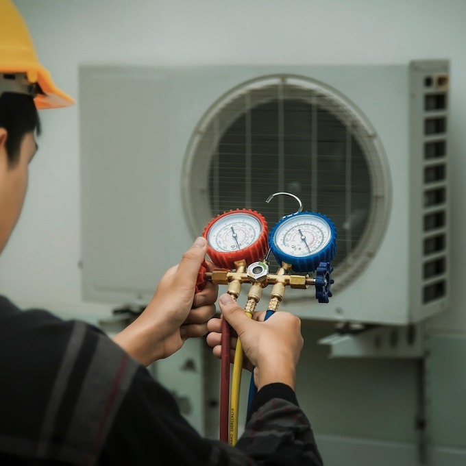 An HVAC repairman is calibrating an air conditioner.